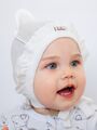 Трикотажный ажурный чепчик уголком с с рюшей для новорожденных девочек молочного цвета
