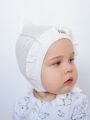 Трикотажный ажурный чепчик уголком с с рюшей для новорожденных девочек молочного цвета